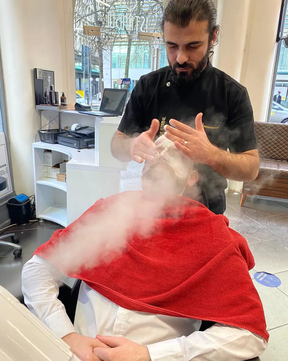 A hot towel steaming over a customer in the barber's chair