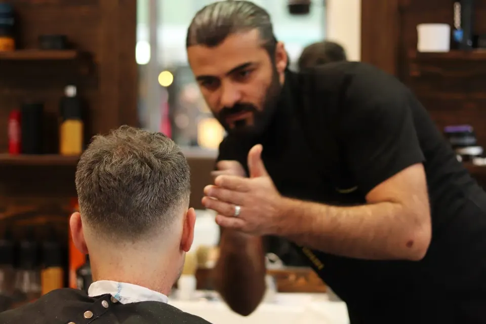 A barber talking a customer through his cut at the mirror